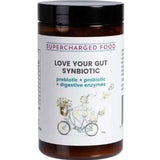 A brown jar labeled Supercharged Food Love Your Gut Synbiotic Powder 120g, featuring prebiotics, probiotics, and digestive enzymes. The label shows a person riding a bicycle with flowers.