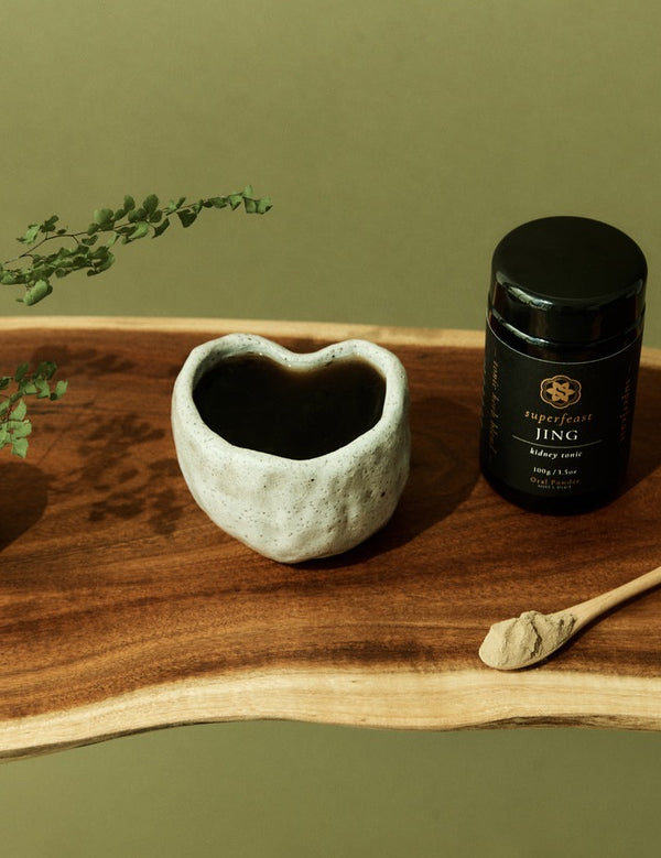 SuperFeast JING beside a prepared tonic in a daily ritual