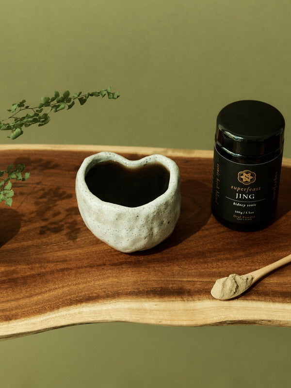 SuperFeast JING beside a prepared tonic in a daily ritual