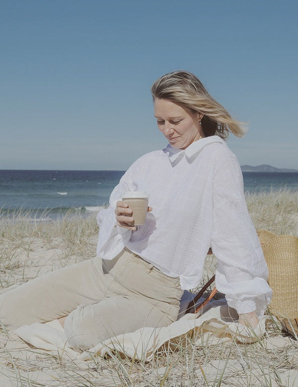 Woman enjoying a Reishi tonic by the sea