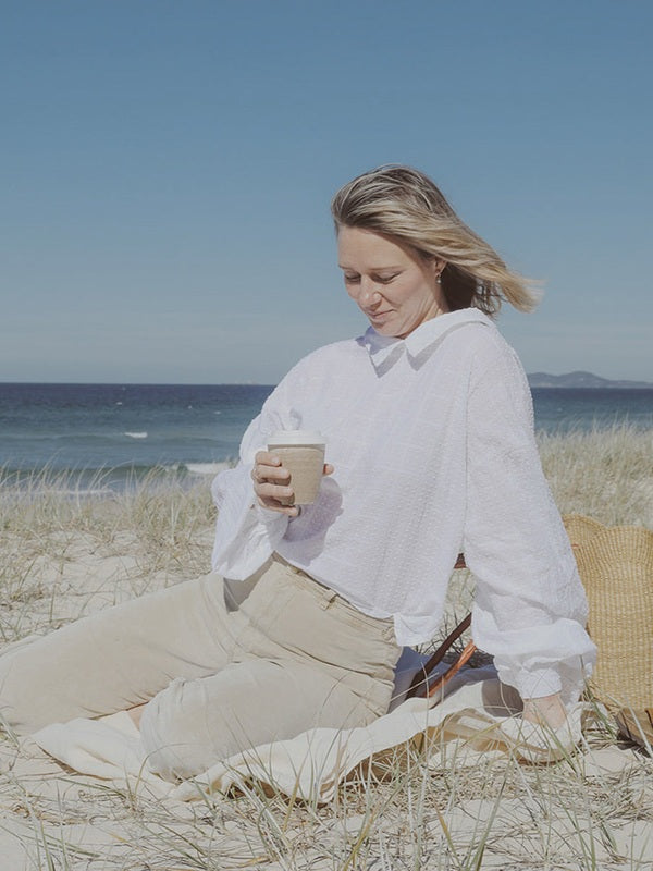 Woman enjoying a Reishi tonic by the sea