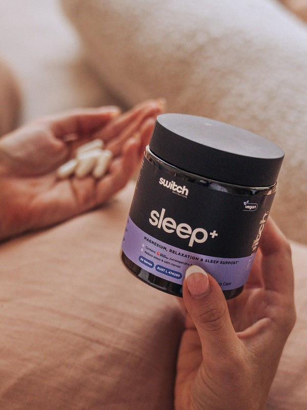 Close-up of Switch Nutrition Sleep+ Capsules jar and capsules in hand