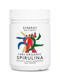 White Synergy Natural Organic Spirulina powder tub with a broad ribbed white lid and colourful red, green, blue and yellow figures above black 'SPIRULINA' lettering.