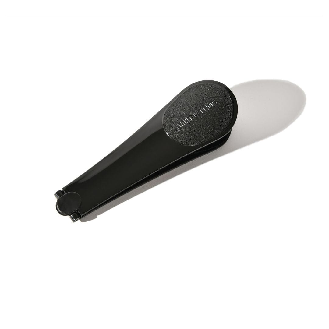 Black Three Warriors Self-Tan Back Applicator folded in half, with its tapered handles together and a rounded end casting a long shadow.