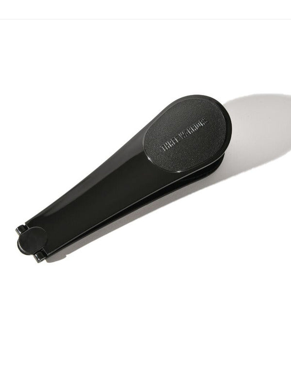 Black Three Warriors Self-Tan Back Applicator folded in half, with its tapered handles together and a rounded end casting a long shadow.