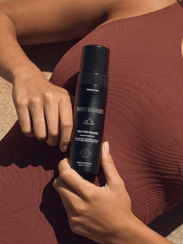 Self Tan Mousse held against bronzed skin