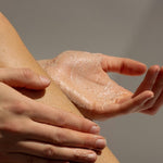 Hands applying Tasmanian Sand Scrub to a leg