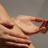 Hands applying Tasmanian Sand Scrub to a leg