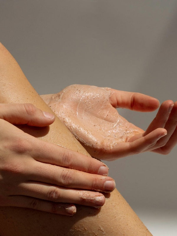 Hands applying Tasmanian Sand Scrub to a leg
