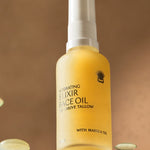 Golden Thrive Tallow Hydrating Elixir Face Oil 50ml bottle standing among glossy oil droplets in warm amber light.
