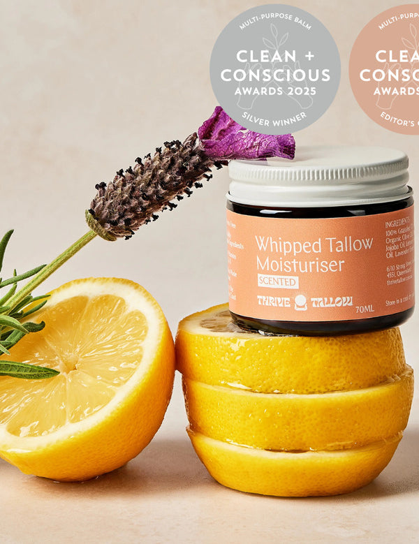 Thrive Tallow Scented Whipped Tallow Moisturiser jar styled with fresh lemon halves and lavender, with Clean and Conscious Awards badges above.