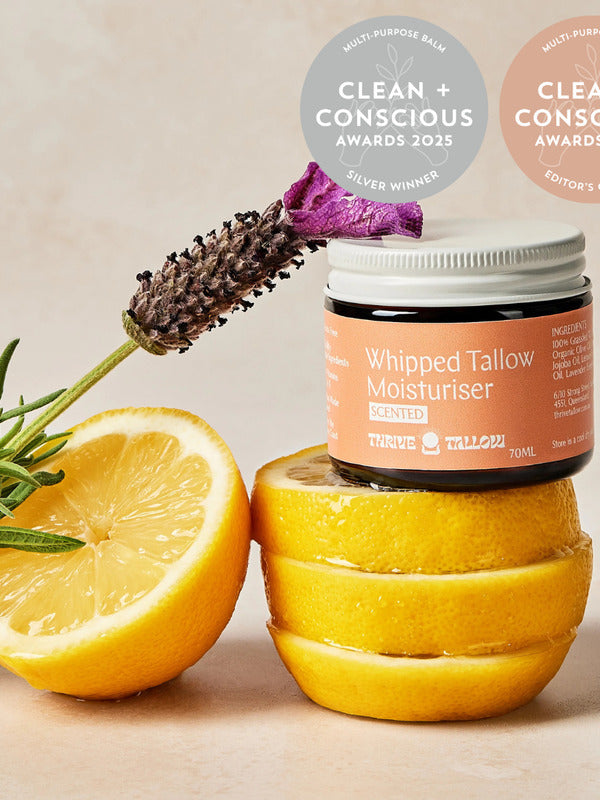 Thrive Tallow Scented Whipped Tallow Moisturiser jar styled with fresh lemon halves and lavender, with Clean and Conscious Awards badges above.