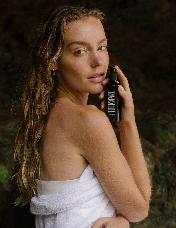 Woman holding Tuttofare Cleansing Oil beside her face