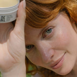 Close-up woman holding Tuttofare Holy Grail Tallow Balm beside her face