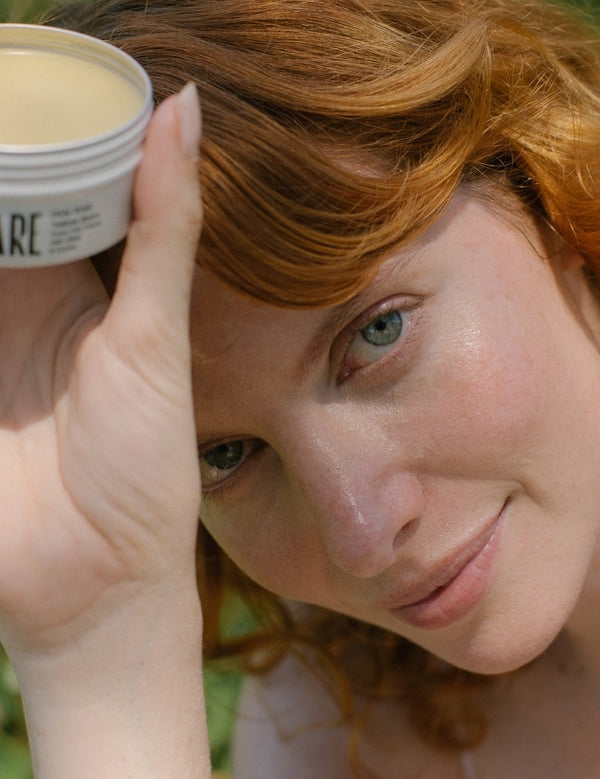 Close-up woman holding Tuttofare Holy Grail Tallow Balm beside her face