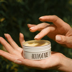 Hand holding an open tin of Tuttofare Holy Grail Tallow Balm