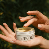 Hand holding an open tin of Tuttofare Holy Grail Tallow Balm