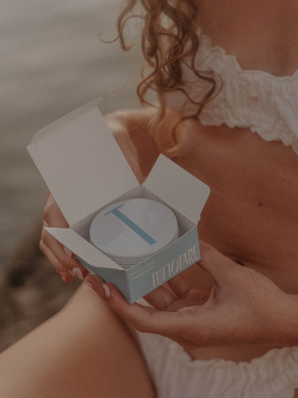Hand holding an open tin of Tuttofare Roman Blue Tallow Balm