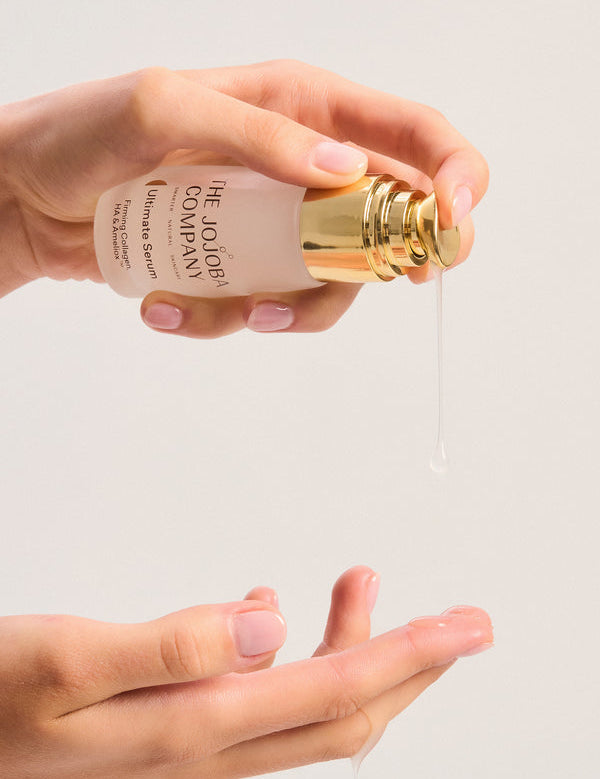 Hand holding a bottle of The Jojoba Company Ultimate Serum
