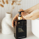 Hand reaching for Vanessa Megan Blood Orange and Vetiver Body Wash