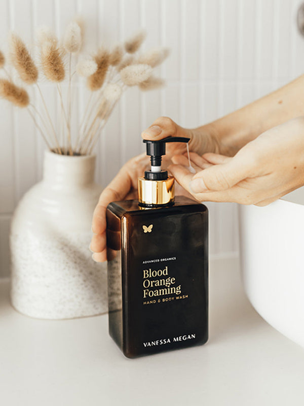 Hand reaching for Vanessa Megan Blood Orange and Vetiver Body Wash