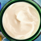 Open green glass jar of Weleda Blue Gentian and Edelweiss Contouring Night Cream viewed from above, showing the rich white cream texture.
