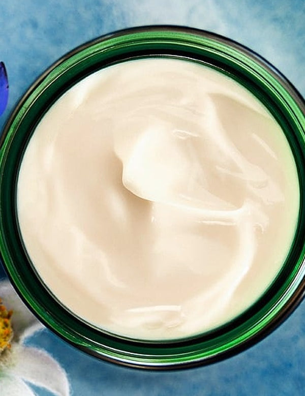 Open green glass jar of Weleda Blue Gentian and Edelweiss Contouring Night Cream viewed from above, showing the rich white cream texture.