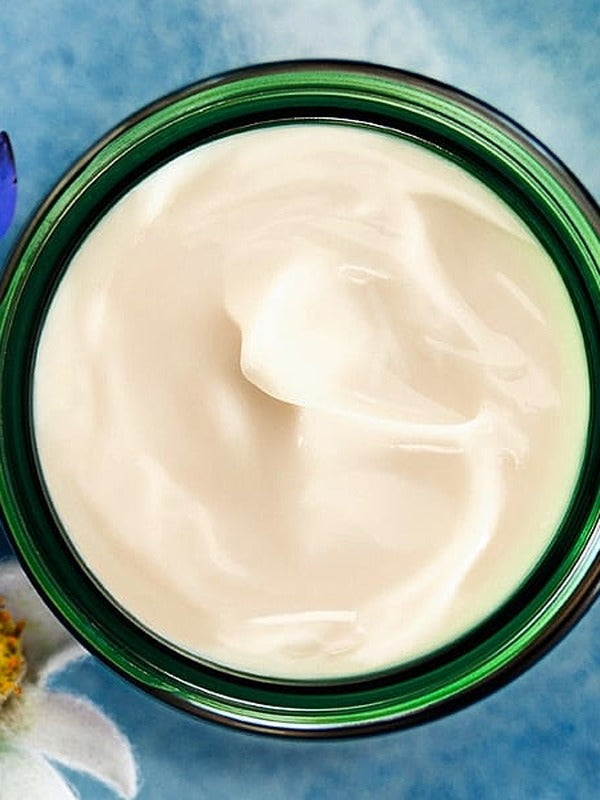 Open green glass jar of Weleda Blue Gentian and Edelweiss Contouring Night Cream viewed from above, showing the rich white cream texture.
