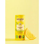 Deodorant Stick Citrus-Bergamot next to a slice of lemon, against yellow background.
