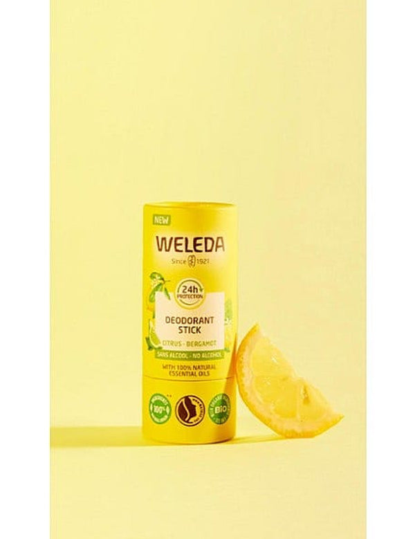 Deodorant Stick Citrus-Bergamot next to a slice of lemon, against yellow background.