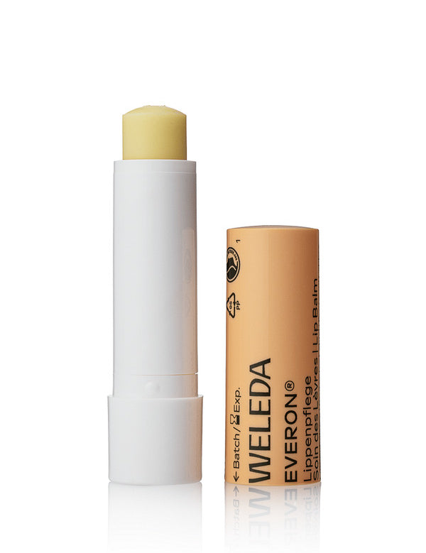 Open Weleda Everon Lip Balm stick standing beside its brown printed cap on a clean white background.