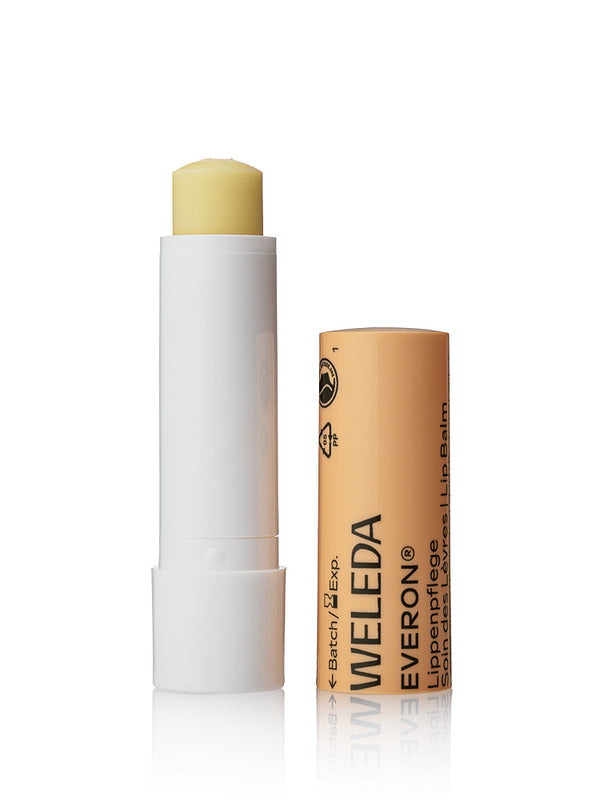 Open Weleda Everon Lip Balm stick standing beside its brown printed cap on a clean white background.