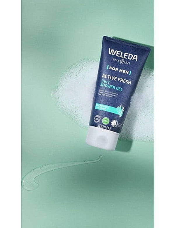 Tube of Weleda Men Active Fresh3-in-1 Shower Gel with eucalyptus and vetiver, surrounded by foam and gel on a light green background.