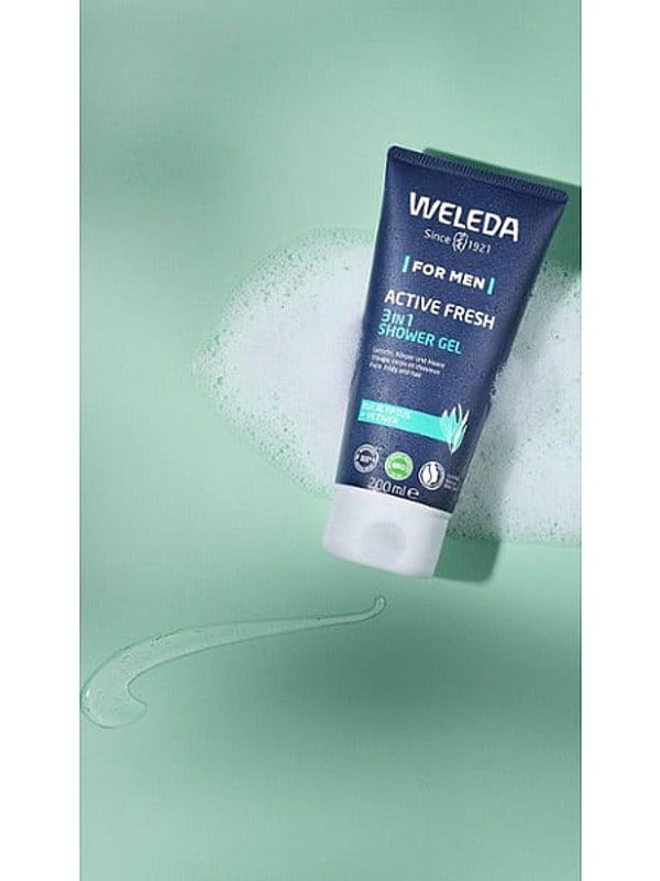 Tube of Weleda Men Active Fresh3-in-1 Shower Gel with eucalyptus and vetiver, surrounded by foam and gel on a light green background.