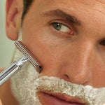 Man shaving in a mirror with Weleda For Men Shaving Cream lathered across his face.