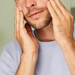 Man massaging Weleda Men 5 in 1 Multi-Action Serum into both cheeks during his skincare routine.