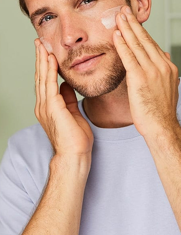 Man massaging Weleda Moisture Cream for Men into both cheeks during his morning skincare routine.