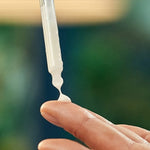 Firming face serum pipette being squeezed onto a finger before application.
