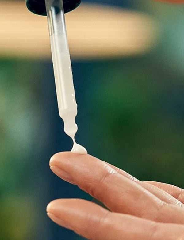 Firming face serum pipette being squeezed onto a finger before application.