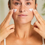 Woman applying Weleda Sensitive Soothing Moisturiser to both cheeks with her fingertips.