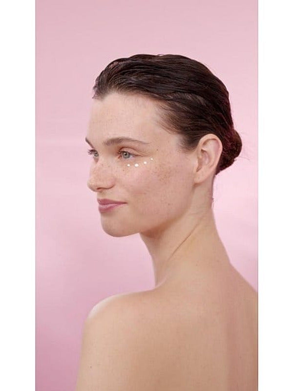 Woman's profile with Smoothing Wild Rose & White Tea cream on her face in a pink background.