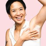 Smiling woman applying WooHoo Armpit Detox Mask to her underarm