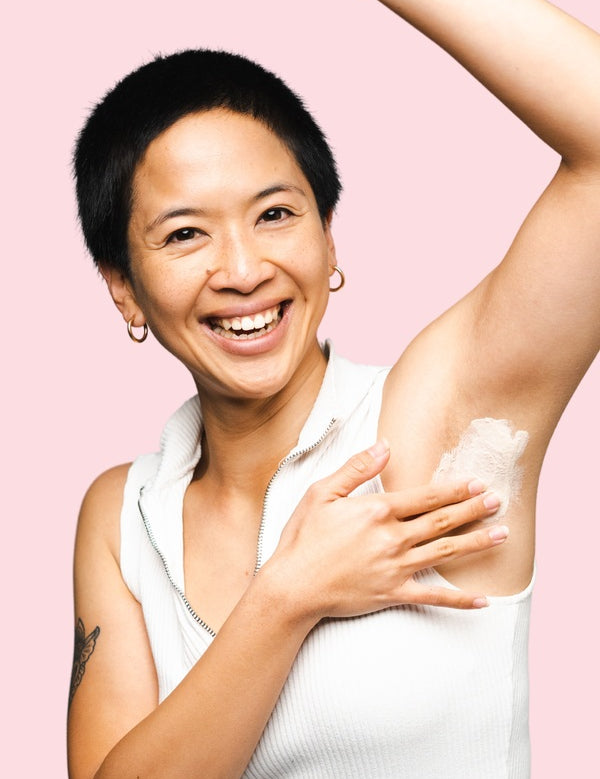 Smiling woman applying WooHoo Armpit Detox Mask to her underarm
