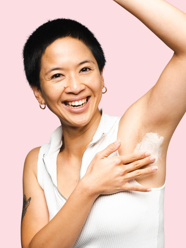 Smiling woman applying WooHoo Armpit Detox Mask to her underarm