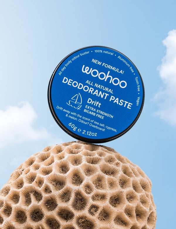 WooHoo Drift deodorant paste balanced above coral against a blue sky