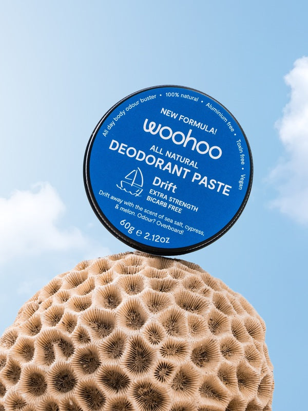WooHoo Drift deodorant paste balanced above coral against a blue sky