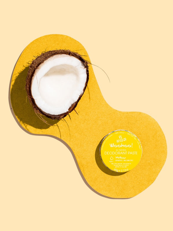 WooHoo Mellow deodorant paste styled with coconut on a yellow background