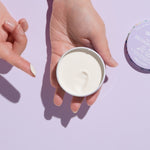 Open WooHoo Pop deodorant paste held in two hands against a purple background
