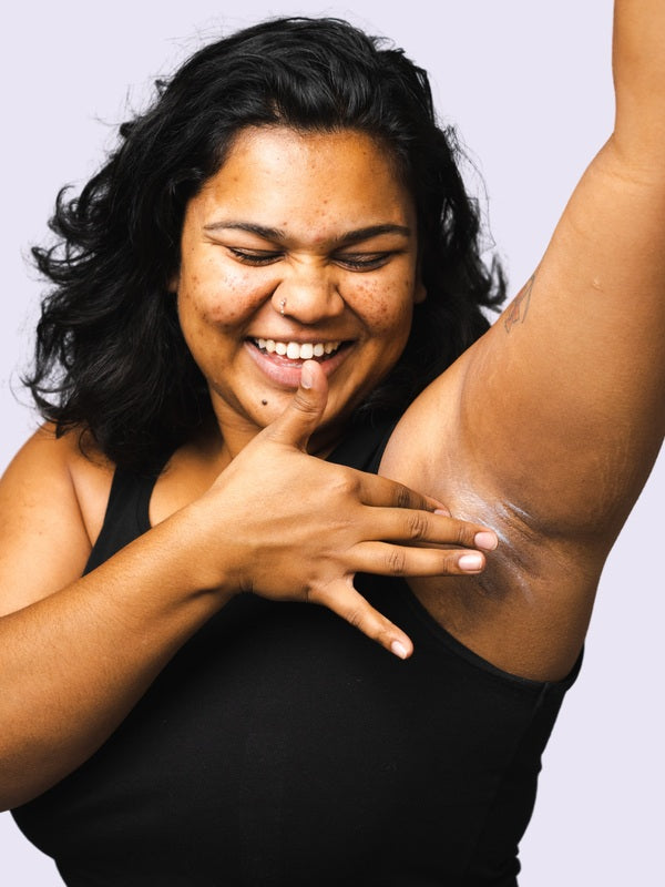 Woman applying WooHoo Pop deodorant paste to her underarm