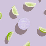 WooHoo Pop deodorant paste styled with fresh lime wedges on a purple background